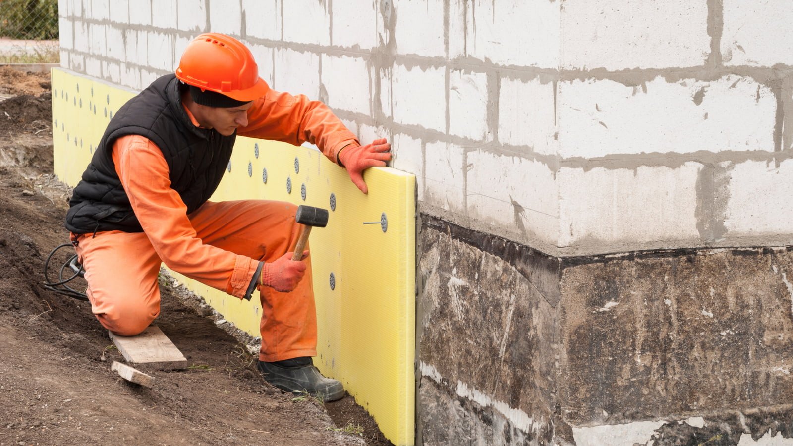 man waterproofing a house to prevent water damage